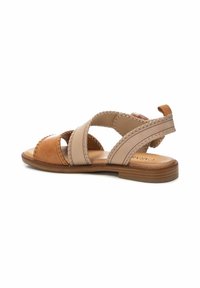 Sandalia de cuero en tonos marrón y beige con tiras superpuestas, detalles de costura, suela plana y un pequeño tacón marrón.