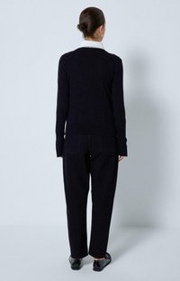 Pull en maille navy avec un col blanc, associé à un pantalon navy assorti. Texture lisse et coupe décontractée, avec des poches arrière sur le pantalon.