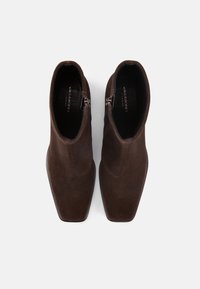 Brązowe botki zamszowe za kostkę z kwadratowym noskiem i zamkami po bokach. Gładka faktura, minimalistyczny design i subtelne oznaczenie wewnątrz.