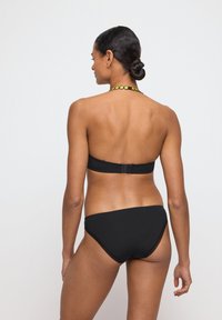 Zwart bikini-set met een strapless top met een sluiting aan de achterkant en een bijpassende low-rise onderkant. Soepele stof met minimale ontwerpelementen.