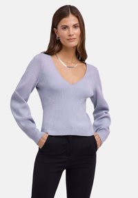 Jasnofioletowy prążkowany sweter z dekoltem w serek, dopasowaną talią i długimi rękawami, zestawiony z czarnymi spodniami. Gładka faktura i casualowy styl.