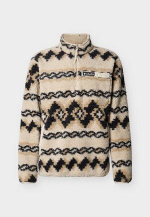 Beežide toonides fliispusa mustade ja beežide geomeetriliste mustritega, poollukuga kaelusega ja rinnataskuga, millel on logokaunistus. Pehme ja tekstuuriga kangas.