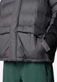 Grå puffjacka med matt finish, som har kviltade sektioner och svarta accenter. Inkluderar två framfickor och en ärmdesign med manschett.