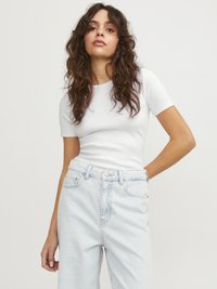 Weißes, geripptes Kurzarmoberteil kombiniert mit hellblauen, hoch taillierten Jeans. Der Stoff wirkt weich und hat ein tailliertes Design mit dezenten Nähten.