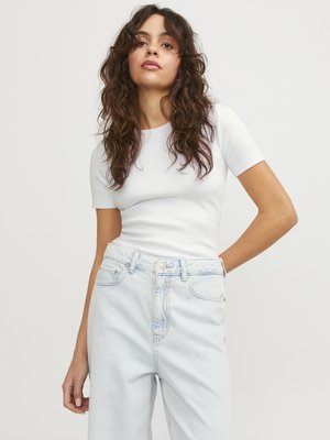 Hvit ribbet kortermet topp kombinert med lyseblå høytlivsjeans. Stoffet ser mykt ut med en tettsittende design og subtile sømdetaljer.
