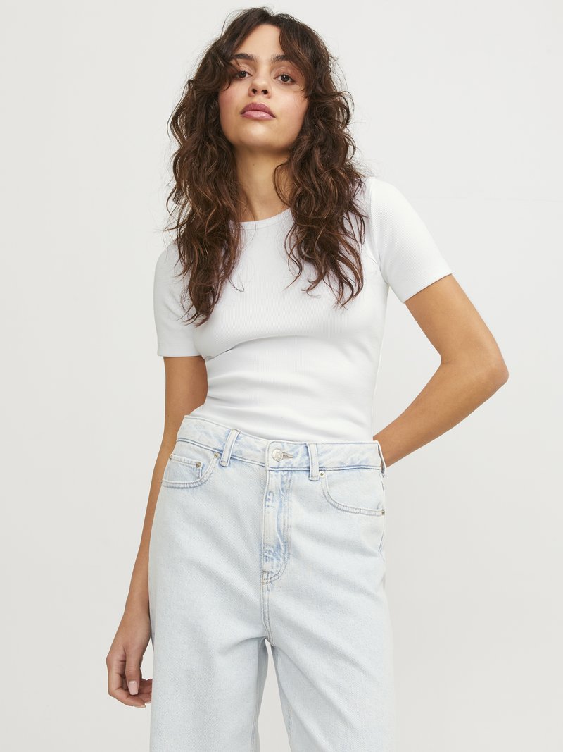 Weißes, geripptes Kurzarmoberteil kombiniert mit hellblauen, hoch taillierten Jeans. Der Stoff wirkt weich und hat ein tailliertes Design mit dezenten Nähten.