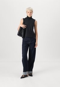 Top sin mangas negro con cuello alto, jeans oscuros de pernera ancha con puños, bolso negro y zapatos planos puntiagudos. Elementos de diseño simples y limpios.