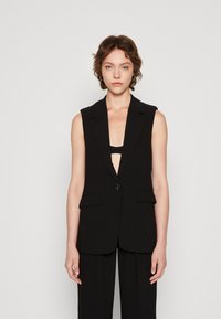 Black sleeveless blazer with a deep V-neck, front button closure, and two front pockets. Smooth fabric with a tailored silhouette.