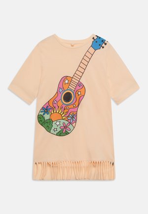 Lyse ferskenfarvet kortærmet top med frynsekant og et farverigt guitargrafik dekoreret med sol, blomster, stjerner og grønt.