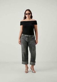 Μαύρο κορμάκι χωρίς ώμους, γκρίζες τζιν παντελόνες ψηλόμεσες με γυρισμένα στρίφωμα, ασημί πέδιλα με λουράκια και σκούρα γυαλιά ηλίου. Λείος ύφασμα και εφαρμοστή σχεδίαση.