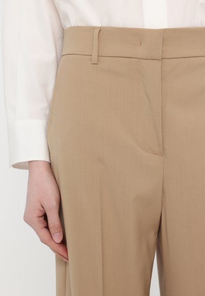 Pantaloni bej, croiți cu un finisaj neted. Au picioare drepte, buzunare laterale și un tiv plat cu bucle pentru curea.