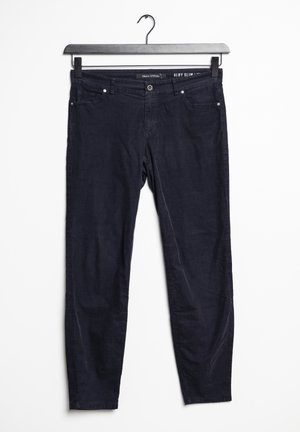 Ciemnoniebieskie spodnie typu slim fit wiszące na czarnym wieszaku na białym tle.