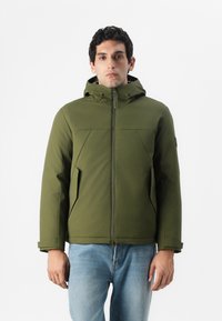 Olivgrüne, kapuzente Jacke mit Reißverschluss, die zwei Seitentaschen und ein strukturiertes, schlankes Design aufweist. Der Stoff wirkt glatt und langlebig.