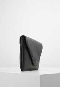 Černé kožené psaníčko s texturovaným povrchem a trojúhelníkovým klopovým zapínáním. Jednoduchý, obdélníkový tvar s hladkým povrchem.