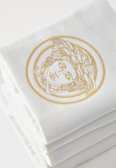Prosop alb cu un design circular brodat cu fir auriu, prezentând o față și detalii complexe ale părului. Textură moale și pliat ordonat.