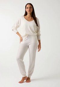 Ensemble de vêtements d'intérieur en tricot crème, composé d'un haut ample et d'un pantalon à taille élastique. Comprend des poignets côtelés et une taille à cordon pour un ajustement.