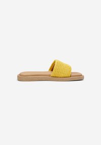 Sandale slide avec une semelle plate beige et une large bride tissée jaune traversant le pied, montrée de profil sur fond blanc.