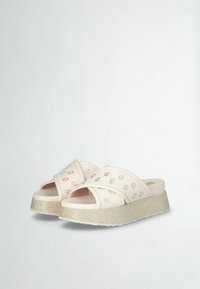 Sandali platform bianchi con cinturini incrociati, caratterizzati da un sottile motivo impresso e una suola a cuneo glitterata. Texture liscia con finitura opaca.