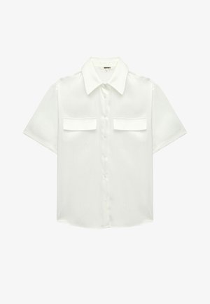 Camisa blanca de manga corta con botones, cuello puntiagudo y dos bolsillos frontales con solapa, hecha de tela ligera y texturizada.