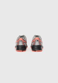 Baskets de sport grises et noires avec des accents orange, dotées d'une tige en maille, d'un bon soutien au talon et d'une semelle texturée pour l'adhérence.