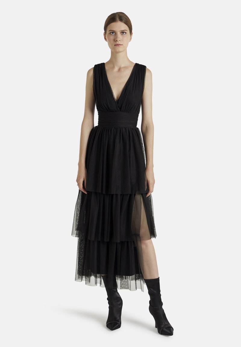 Robe noire sans manches avec un décolleté en V profond, jupe en tulle superposée et taille cintrée. Possède une texture douce et une silhouette fluide.