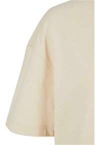 Ljusbeige t-shirt med kort ärm och avslappnad passform, tillverkad av mjukt bomullsmaterial med en slät textur. Något sänkta axelsömmar.