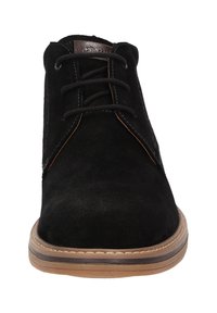 Stivaletti alla caviglia in pelle scamosciata nera con punta rotonda, design con lacci, suola marrone a contrasto e dettagli cuciti lungo il bordo.