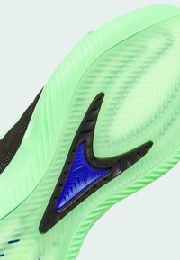 Semelle de chaussure en caoutchouc vert avec motifs texturés ; comporte un accent noir et un élément de design triangulaire bleu pour une meilleure adhérence.