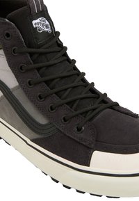 Czarno-szare sneakersy Vans z welurową i płócienną cholewką, z czarnymi sznurowadłami, naszywką z logo oraz teksturowaną gumową podeszwą.