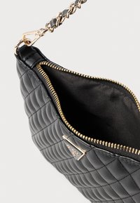 Czarna pikowana torba na ramię z złotym zamkiem błyskawicznym i okuciami, z plecionym łańcuszkiem na ramię i podszytym wnętrzem.