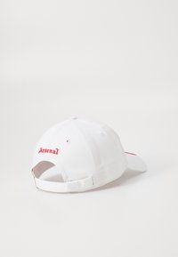 White baseball cap made of cotton, featuring red embroidered "Arsenal" text on the back, adjustable strap, and a curved visor.
