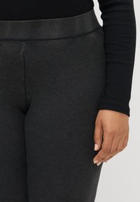 Fekete bordázott leggings, puha tapintással és rugalmas derékrésszel, testhez simuló fazonban és sima felülettel.