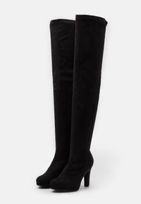 Botas negras por encima de la rodilla hechas de suave ante. Punta redondeada y tacón stiletto alto con costuras visibles en la parte superior.