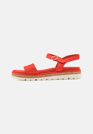 Sandal de tecido vermelho com sola intermédia de cortiça, apresentando uma tira ajustável e uma área dos dedos larga, superfícies texturizadas e uma sola de borracha branca.