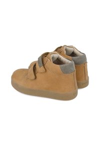 Zapatos altos de ante marrón con correas de Velcro, forro beige y suelas de goma texturizadas. Presentan una textura suave y un diseño de punta redondeada.