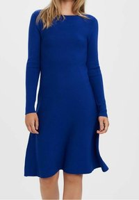 Robe en maille bleue à manches longues avec une texture côtelée. Coupe évasée en A, encolure arrondie et fentes latérales à l'ourlet pour faciliter les mouvements.