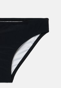 Slip di bikini nero con una texture liscia, fodera interna bianca a contrasto e design a vita bassa. Presenta bordi cuciti per una maggiore durabilità.