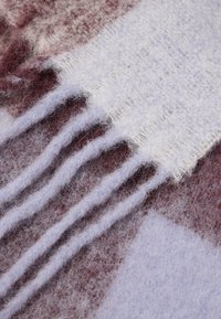 Kootud sall pehmes, helesinises ja marooni toonides. Omab karvaseid tekstuure ja lipsudega servi, segades mustreid lapiteki disainis.