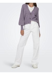 Lila stickad cardigan med V-hals, prydd med två knappar, kombinerad med vita vida byxor och neutrala sneakers. Slät textur.