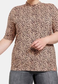 Haut à manches courtes en imprimé léopard dans une teinte rose clair, présentant un col haut et une coupe décontractée, fabriqué en tissu doux et léger.