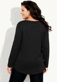 Zwarte top met lange mouwen van zacht, lichtgewicht materiaal. Voorzien van een afgeronde zoom en een losse pasvorm. Getextureerd oppervlak met minimale details.