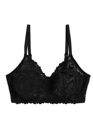 Kobieta nosząca czarny koronkowy stanik z kwiatowymi wzorami i cienkimi regulowanymi ramiączkami, pokazana od klatki piersiowej do brody na neutralnym tle.