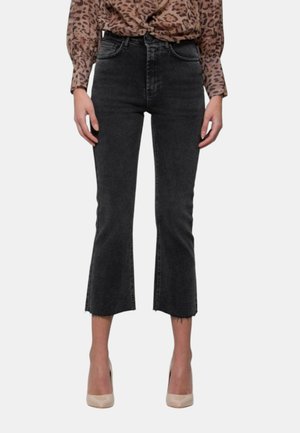 Jeans cropped in denim nero con orlo grezzo e una leggera forma svasata, dotati di tasche frontali e posteriori, abbinati a tacchi alti beige.