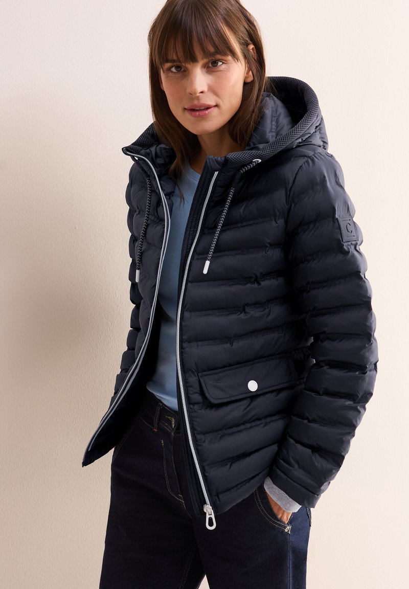 Giacca puffa blu navy con zip frontale, cappuccio regolabile con stringa e polsini elasticizzati. Presenta un'imbottitura orizzontale e una tasca frontale con chiusura a scatto.