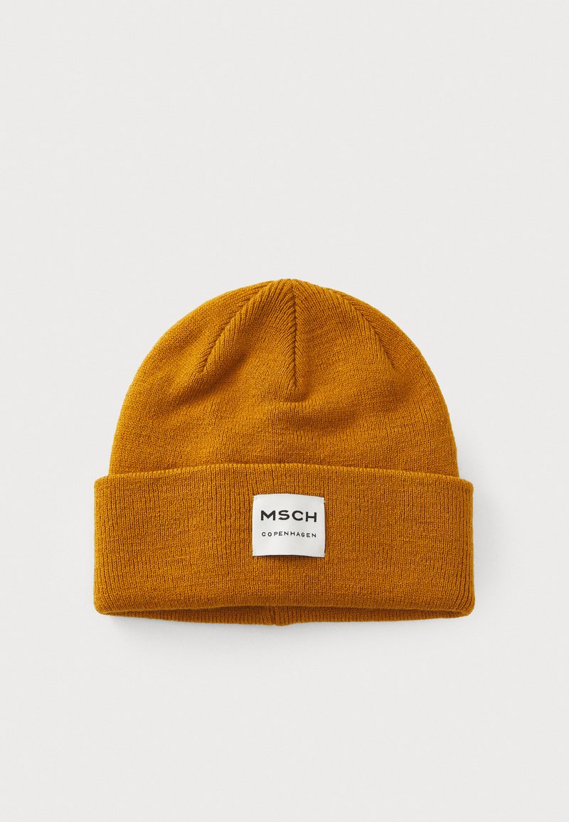Mustard yellow knit beanie hat with a folded cuff, featuring a white label with "MSCH COPENHAGEN" text on the front. Soft texture.