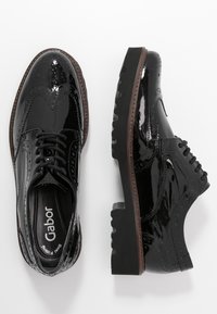 Sorte patentlæder brogues med et tekstureret wingtip-design og en robust gummisål. Har klassisk snøring og kontrasterende brune syninger.