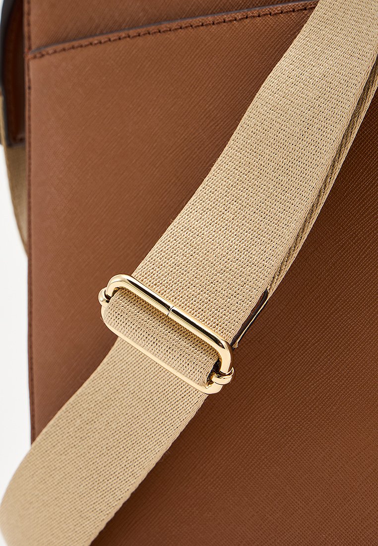 Sangle en tissu beige réglable avec boucle en métal doré attachée à un sac en cuir brun texturé.