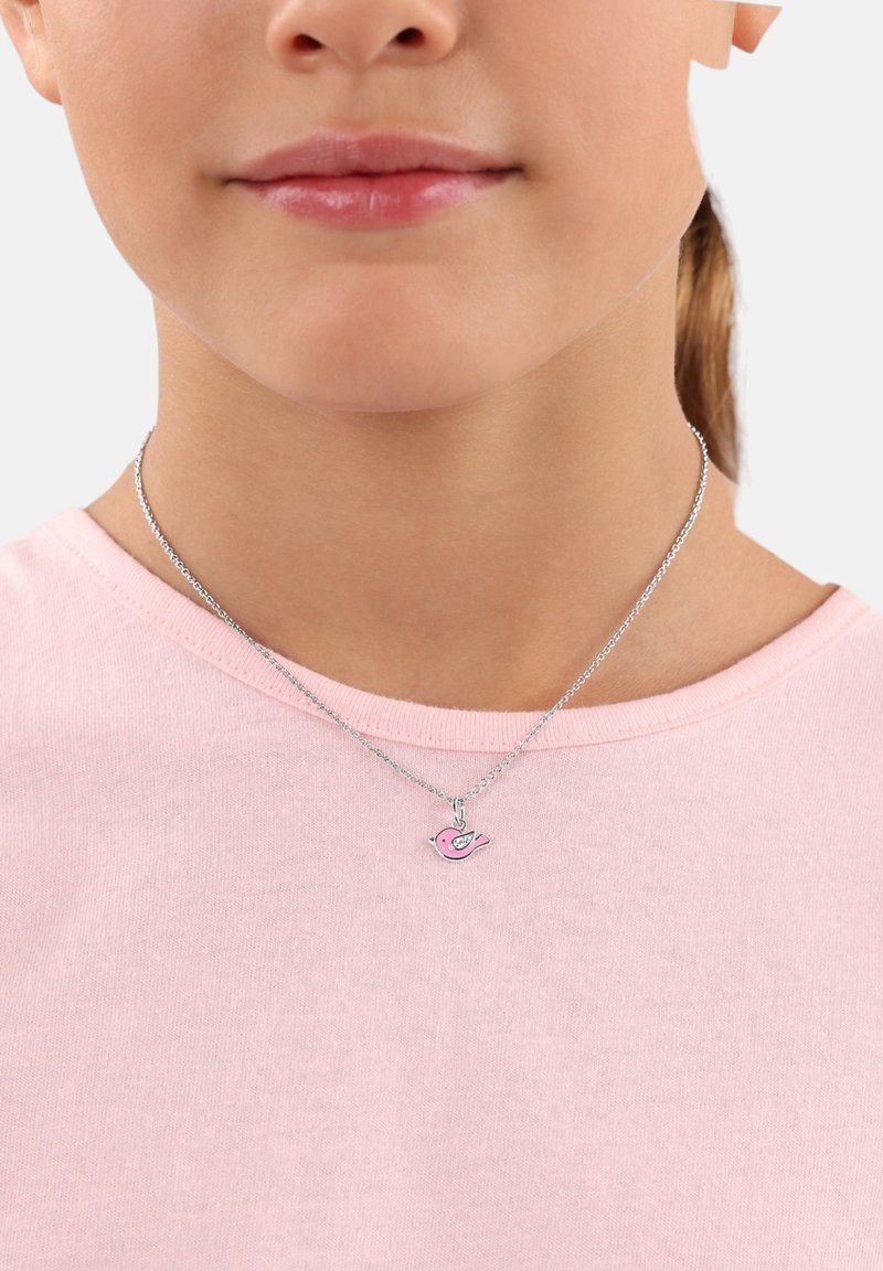 Collana in argento con un ciondolo a forma di uccello rosa con dettagli neri, indossata da una persona con una maglietta rosa chiaro.