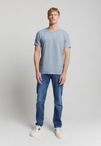 Blauwe gestreepte t-shirt met ronde hals, korte mouwen, gecombineerd met blauwe jeans en witte sneakers. Casual pasvorm, gemaakt van zachte katoen.