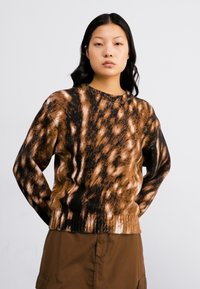 Brown and black patterned sweater made of soft fabric, featuring a round neckline and ribbed hem, styled with a brown skirt.